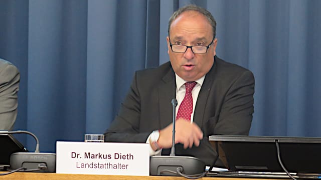 Mann mit Brille und Anzug vor Mikrofon. Mann mit Brille und Anzug vor Mikrofon.