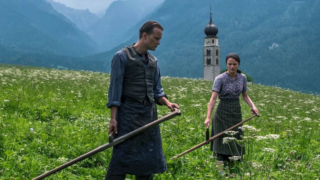Ein Mann und eine Frau arbeiten auf dem Feld. Sie haben Sensen in der Hand. Ein Mann und eine Frau arbeiten auf dem Feld. Sie haben Sensen in der Hand.