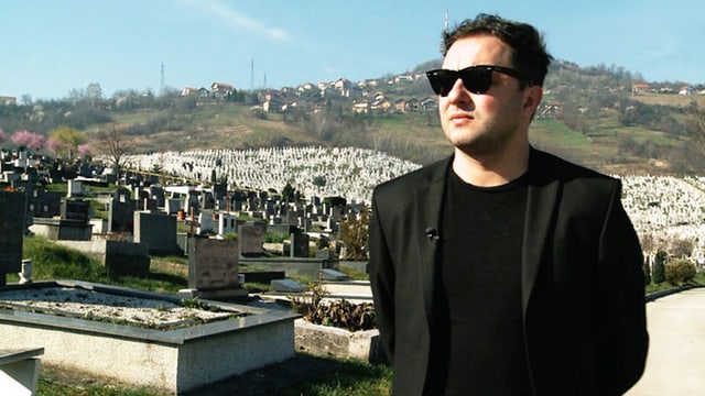 Man sieht Mladen Miljanovic vor einem Friedhof. Man sieht Mladen Miljanovic vor einem Friedhof.