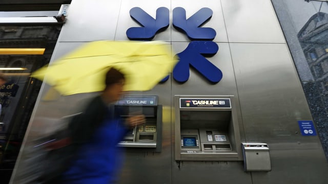 Eine Frau mit Regenschirm geht an einem Bankomat der Royal Bank of Scotland vorbei. Die Bank muss eine weitere Millionen-Busse im Libor-Skandal zahlen. (reuters) Eine Frau mit Regenschirm geht an einem Bankomat der Royal Bank of Scotland vorbei. Die Bank muss eine weitere Millionen-Busse im Libor-Skandal zahlen. (reuters)