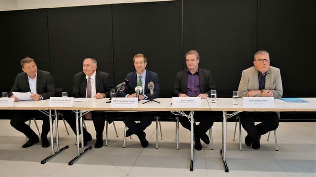 Fünf Personen sitzen an einem Tisch. Fünf Personen sitzen an einem Tisch.