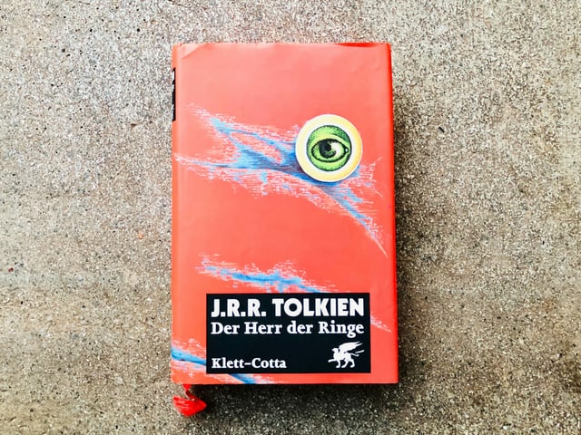 Der Roman «Der Herr der Ringe» von J.R.R. Tolkien liegt auf einem Zementboden Der Roman «Der Herr der Ringe» von J.R.R. Tolkien liegt auf einem Zementboden