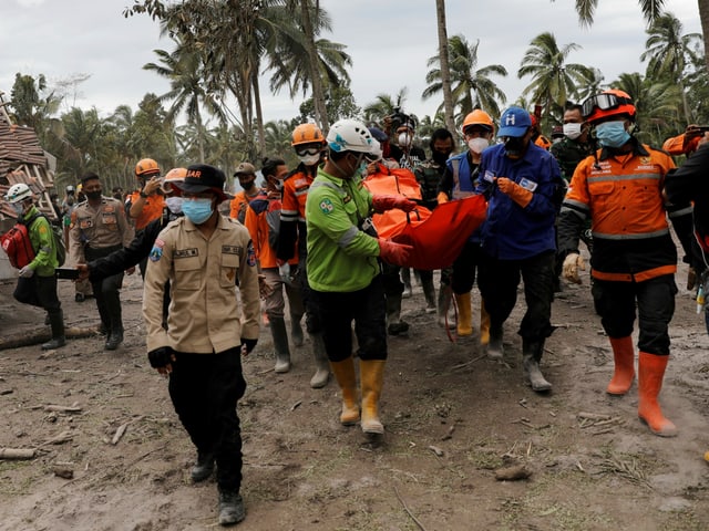 Petugas penyelamat membawa kantong mayat.