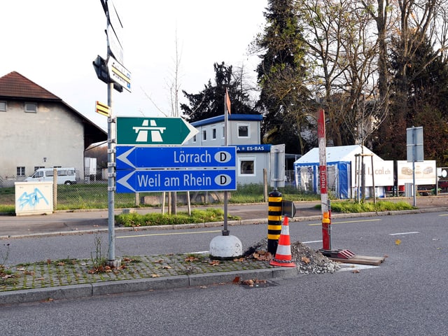 Zwei Schilder weisen auf Lörrach und Weil am Rhein, das Container-Café im Hintergrund.