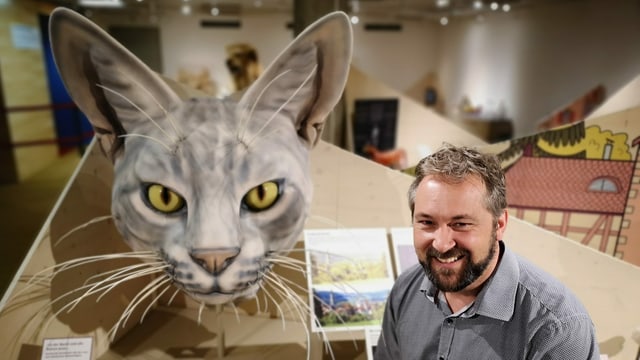 Mann neben grossem Katzenkopf Mann neben grossem Katzenkopf
