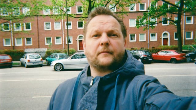 Mann auf der Strasse – im Hintergrund eine Häuserzeile. Mann auf der Strasse – im Hintergrund eine Häuserzeile.