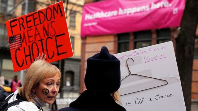 Zwei Demonstrantinnen. Sie halten Schilder mit den Aufschriften "Freedom means Choice" und "Parenthood Centers Focus on Prevention - this ist not a choice" mit einem aufgeklebten Kleiderbügel. Zwei Demonstrantinnen. Sie halten Schilder mit den Aufschriften "Freedom means Choice" und "Parenthood Centers Focus on Prevention - this ist not a choice" mit einem aufgeklebten Kleiderbügel.