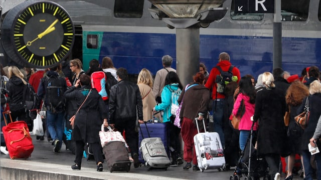 Personen mit Rollkoffern auf einem Bahnsteig. Personen mit Rollkoffern auf einem Bahnsteig.