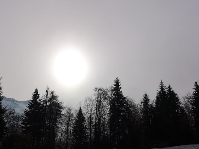 Die Sonne schimmert durch eine dünne Wolkenschicht.