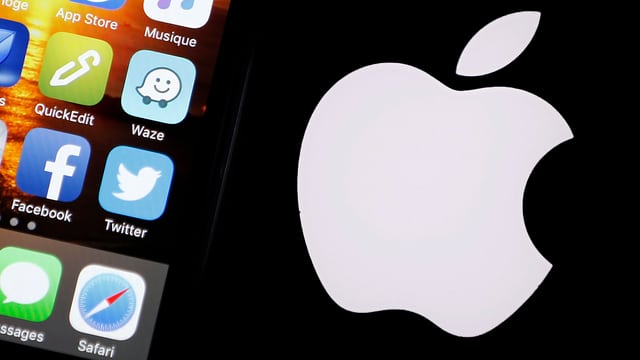 Ausschnitt von einem iPhone vor schwarzem Hintergrund mit dem weissen angebissenen Apfel, dem Firmenlogo von Apple. Ausschnitt von einem iPhone vor schwarzem Hintergrund mit dem weissen angebissenen Apfel, dem Firmenlogo von Apple.