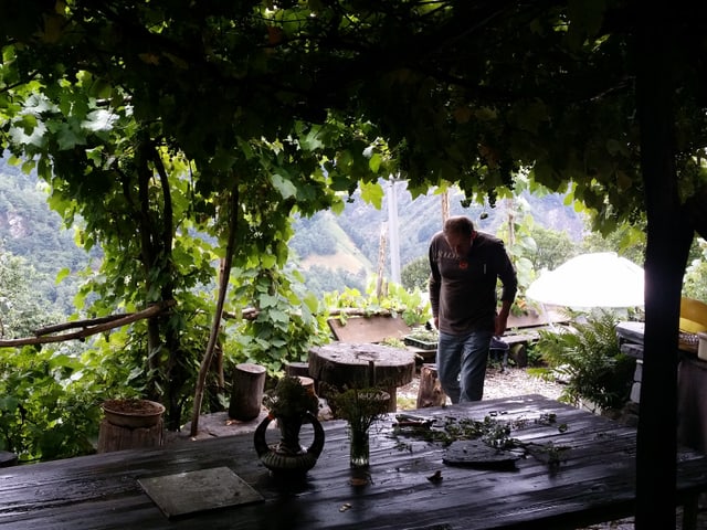 Ein Holztisch unter einer Pergola mit Sicht in das Tal.