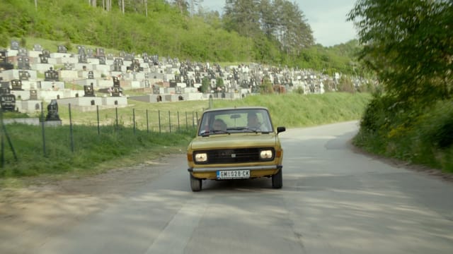 Ein gelbes, altes Auto fährt auf einer verlassenen Landstrasse. Ein gelbes, altes Auto fährt auf einer verlassenen Landstrasse.