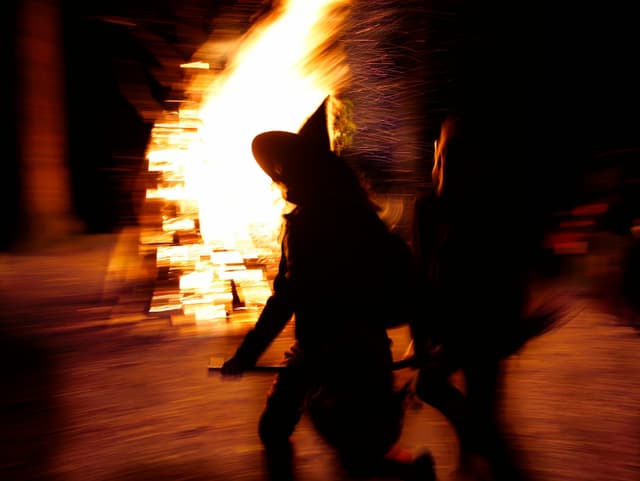 Als Hexen verkleidete Menschen rennen um ein Feuer Als Hexen verkleidete Menschen rennen um ein Feuer