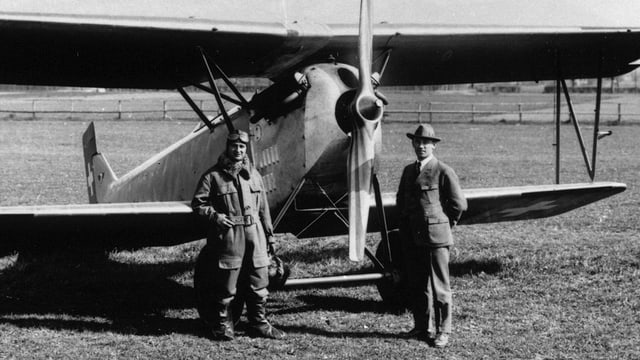 Alter Doppeldecker, davor Pilot und mann mit Hut. Alter Doppeldecker, davor Pilot und mann mit Hut.