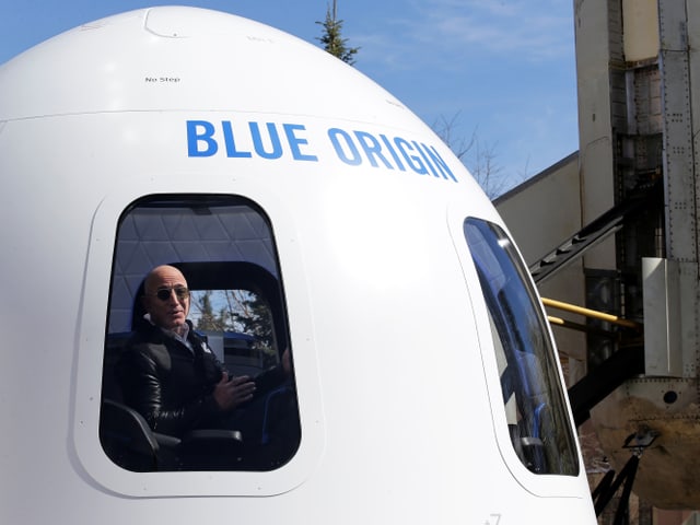 Jeff Bezos schaut aus dem Fenster einer Raumkapsel. Jeff Bezos schaut aus dem Fenster einer Raumkapsel.