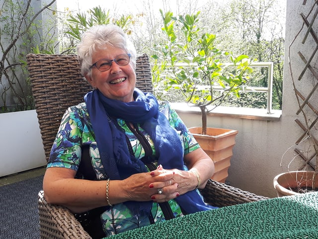 Eine ältere lachende Frau auf einer Terrasse. Eine ältere lachende Frau auf einer Terrasse.