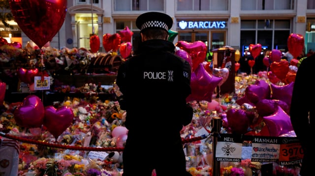 Polizist vor Blumen in Manchester. Polizist vor Blumen in Manchester.