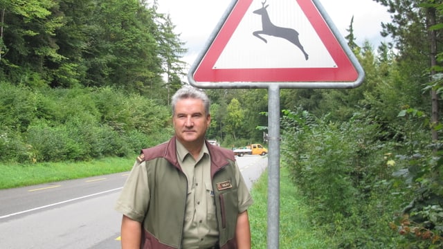 Ein Mann steht an einer Strassen vor einem Schild. Ein Mann steht an einer Strassen vor einem Schild.