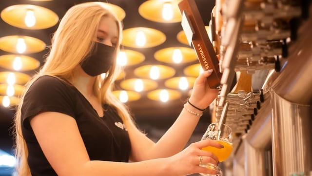 Barmitarbeiterin eines Hotels schenkt ein Bier ein.