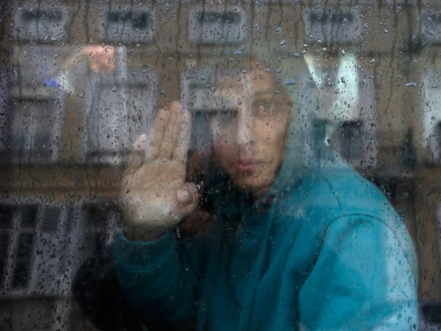 Minderjähriger Flüchtling an Fensterscheibe.