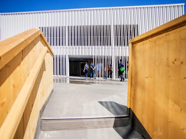 Eine Treppe mit einem Geländer aus Holz. Hinten ist ein weisses Gebäude. Eine Treppe mit einem Geländer aus Holz. Hinten ist ein weisses Gebäude.