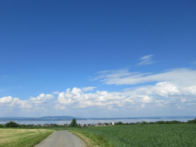 Kleine Quellwolken stehen über dem dem See, sonst ist der Himmel blau.