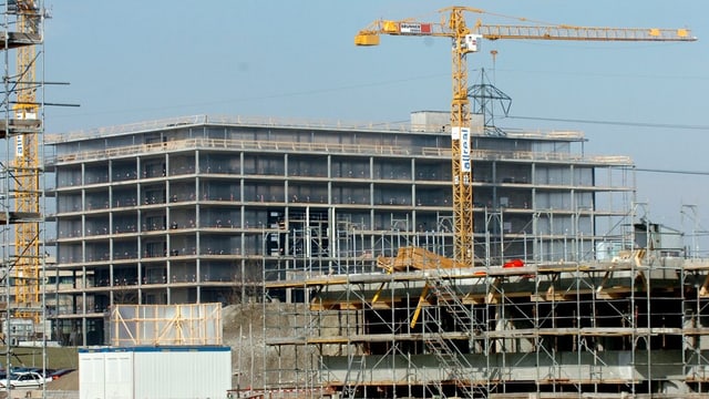 Eine Baustelle mit eine Gebäude im Rohbau und einem Baukran. Eine Baustelle mit eine Gebäude im Rohbau und einem Baukran.