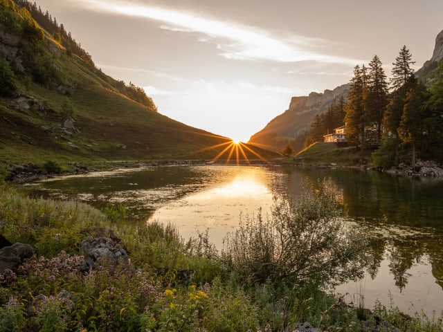 Sonnenaufgang über einem Bergsee in hellen Tönen.