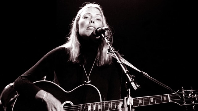 Eine blonde Frau mit Gitarre singt. Eine blonde Frau mit Gitarre singt.