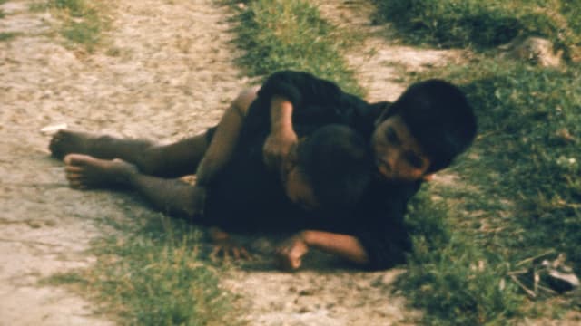 Duc Tran Van und seine Schwester liegen geduckt auf einem Feldweg. Duc Tran Van und seine Schwester liegen geduckt auf einem Feldweg.