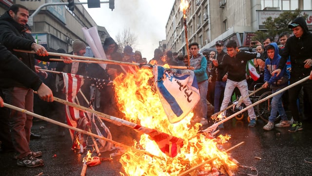 Menschen verbrennen Flaggen der USA und Israel. Menschen verbrennen Flaggen der USA und Israel.