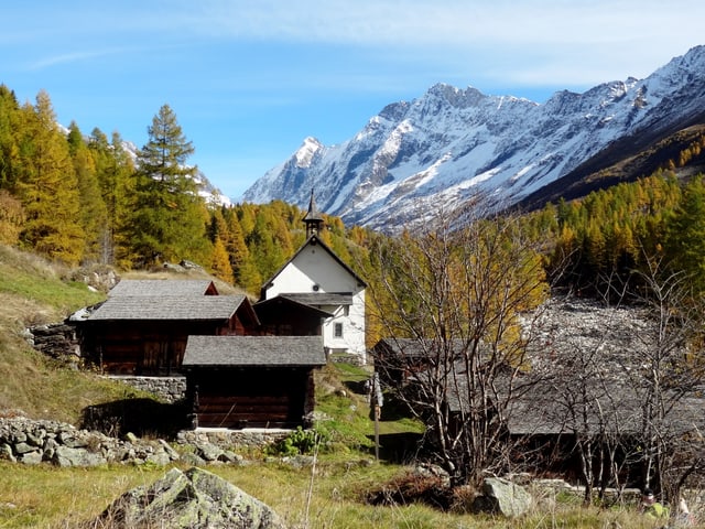 Eine Kapelle, gelbe Bäume, blauer Himmel.