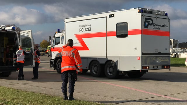 Polizist mit Handy am Ohr vor Polizeiauto Polizist mit Handy am Ohr vor Polizeiauto