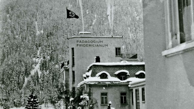 Auf einem Dach weht eine Hakenkreuz-Flagge, im Hintergrund verschneite Berge. Auf einem Dach weht eine Hakenkreuz-Flagge, im Hintergrund verschneite Berge.