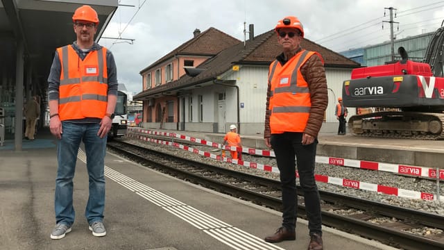 Zwei Männer in orangen Warnwesten stehen auf einem Perron vor dem WSB-Bahnhof in Aarau. Zwei Männer in orangen Warnwesten stehen auf einem Perron vor dem WSB-Bahnhof in Aarau.
