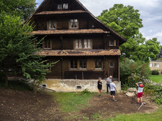Ein altes Haus in Zug, vier Personen stehen davor im Garten. Ein altes Haus in Zug, vier Personen stehen davor im Garten.
