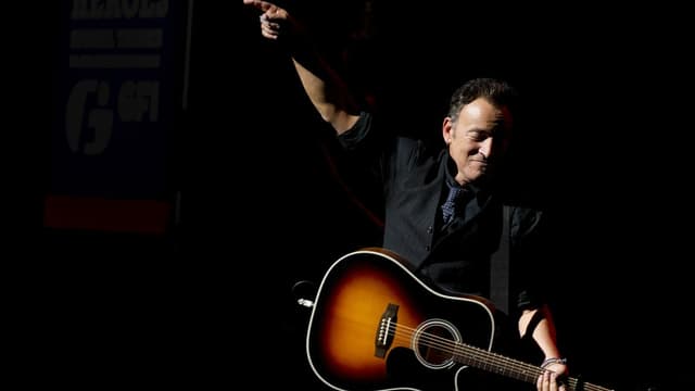 Mann mittleren Alters steht mit Gitarre auf der Bühne Mann mittleren Alters steht mit Gitarre auf der Bühne