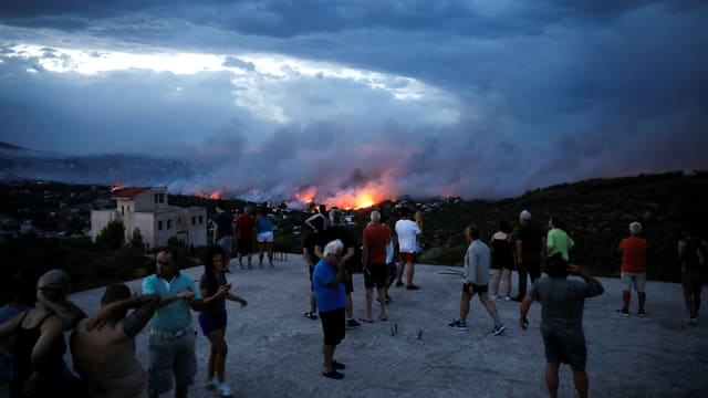 Menschen beobachten von einem Hügel das Feuer Menschen beobachten von einem Hügel das Feuer