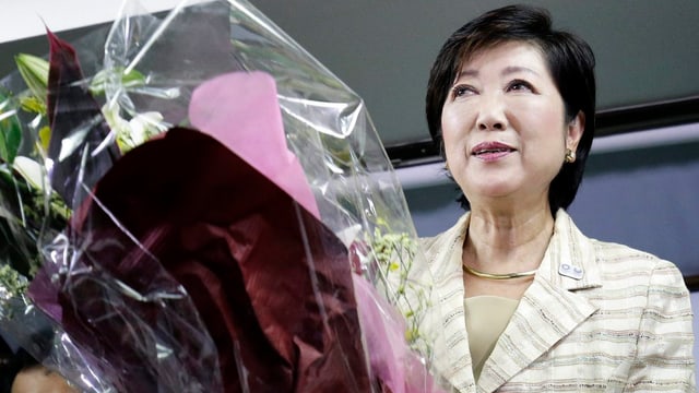 Japanische Frau hält einen Blumenstrauss in der Hand und lächelt. Japanische Frau hält einen Blumenstrauss in der Hand und lächelt.