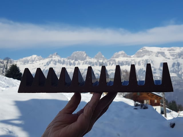 Jemand hält eine Toblerone-Schokolade in der Hand, im Hintergrund die Churfirsten.