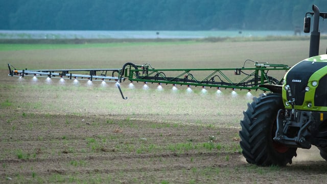 Ein Traktor bringt Spritzmittel auf ein Feld aus Ein Traktor bringt Spritzmittel auf ein Feld aus