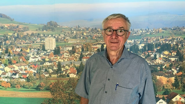 Mann mit Brille steht vor einem Plakat. Mann mit Brille steht vor einem Plakat.