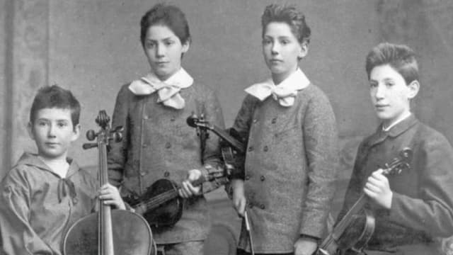 Schwarz-weiss-Fotografie, das vier Kinder mit Streichinstrumenten zeigt. Schwarz-weiss-Fotografie, das vier Kinder mit Streichinstrumenten zeigt.