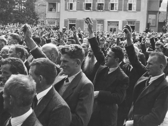 Männer stehen nahe beieinander und heben die Hand um abzustimmen. Männer stehen nahe beieinander und heben die Hand um abzustimmen.