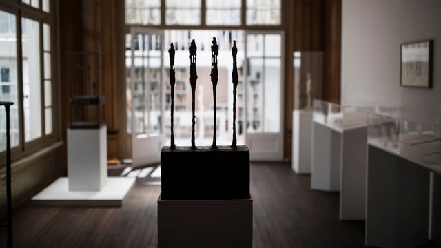 Vier dünne Skulpturen im Gegenlicht in einem Museumsraum mit Virtrinen und Tafeln. Vier dünne Skulpturen im Gegenlicht in einem Museumsraum mit Virtrinen und Tafeln.