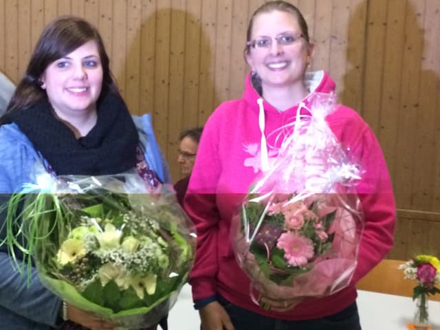 Zwei Frauen tragen einen Blumenstrauss