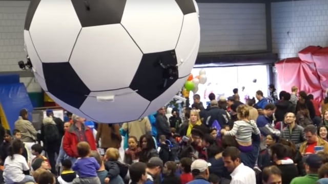 Ballon in Form eines Fussballes schwebt über einer Menschenmenge. Ballon in Form eines Fussballes schwebt über einer Menschenmenge.