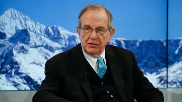 Padoan mit Brille sitzt an vor einem Wandbild mit Schneeberg. Padoan mit Brille sitzt an vor einem Wandbild mit Schneeberg.