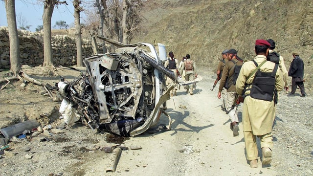 Pakistanische Sicherheitsleute inspizieren den Anschlagsort in Jarmud. Ein total ausgebranntes Fahrzeug der getöteten Begleitpolizisten ist auf dem Bid zu sehen. (keystone) Pakistanische Sicherheitsleute inspizieren den Anschlagsort in Jarmud. Ein total ausgebranntes Fahrzeug der getöteten Begleitpolizisten ist auf dem Bid zu sehen. (keystone)