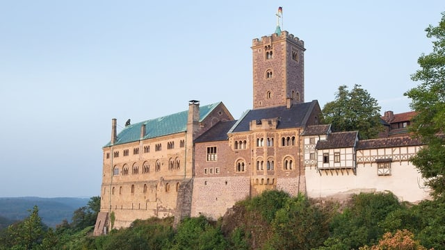 Eine burg mit Turm auf einem bewachsenen Hügel bei schönem Wetter. Eine burg mit Turm auf einem bewachsenen Hügel bei schönem Wetter.